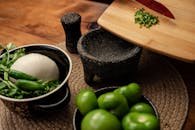 Close-up of fresh Mexican ingredients like tomatillos, onion, and cilantro on a rustic kitchen table.